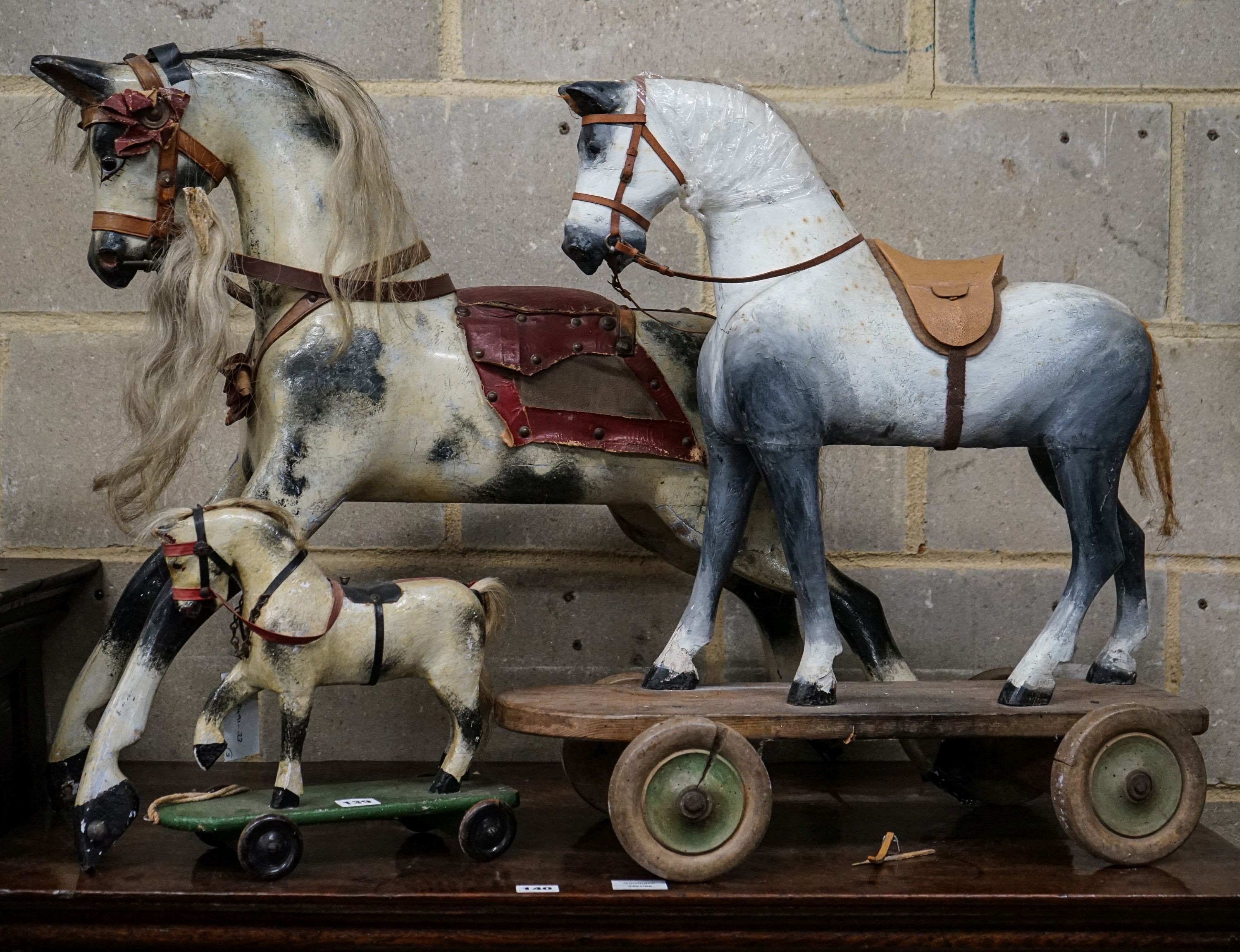 A Victorian carved and painted wood rocking horse, lacking underframe, length 77cm and two painted wood hobby horses, 58cm and 38cm